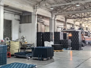 Stacks of black vacuum formed products on wooden pallets in warehouse