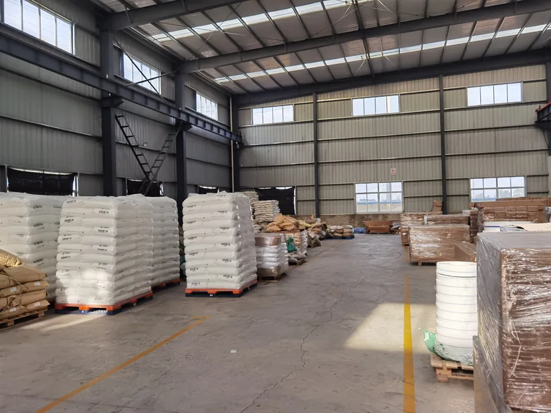 Large warehouse interior with stacked bags of plastic raw materials and finished goods