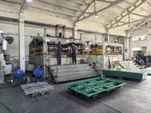 Large vacuum forming machine with workers operating in factory hall